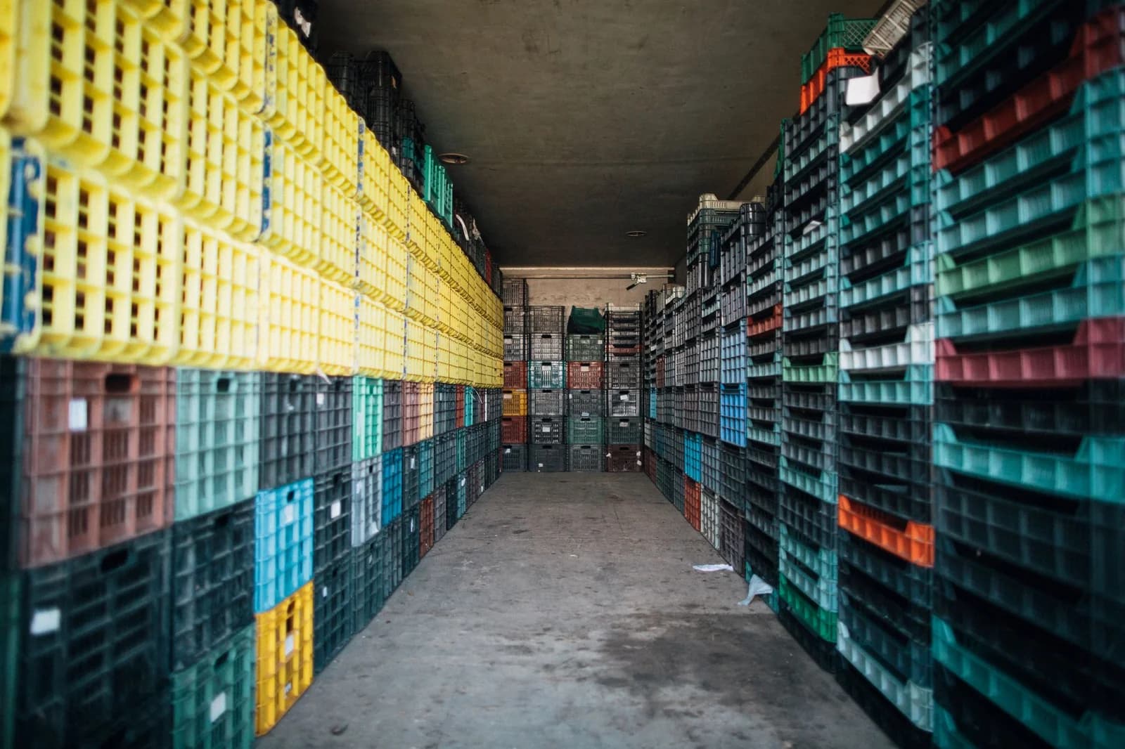Caisses palette plastique monobloc gerbées en rangées dans un entrepôt froid
